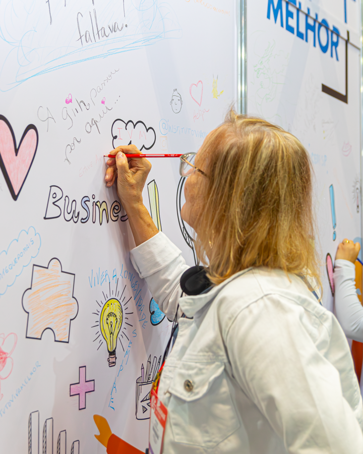 Uma longeva mostrando a sua criatividade no painel de desenho no Fórum da Longevidade 