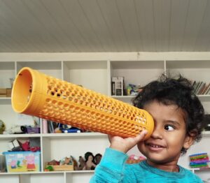 Criança atendida pelo Instituto Viva Melhor, olhando o brinquedo como uma luneta